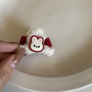 Close-up of white plush rabbit hair claw with red fabric accents and cute soft rubber bunny