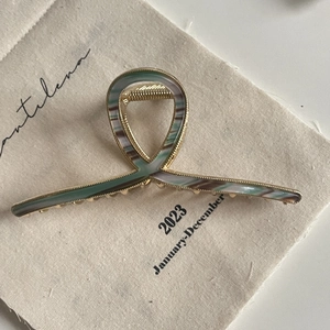 Detail of elegant gold metal hair claw clip with vintage striped resin inlay on fabric
