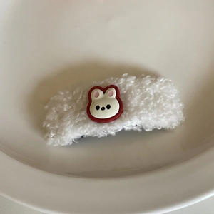 Macro view of cute white teddy plush hair clip with a small cartoon bunny detail