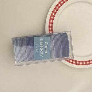 Detailed macro view of various blue high elasticity hair ties in a clear storage box