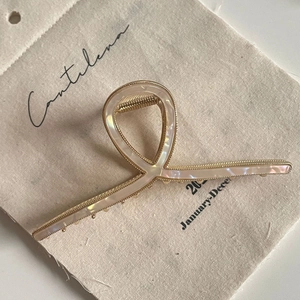 Detailed view of large gold metal hair claw clip with pearl-like shell inlay texture