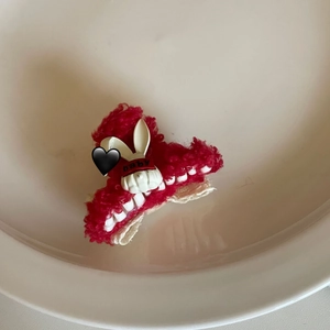 Macro detail of red plush hair claw clip featuring a white bunny with baby text