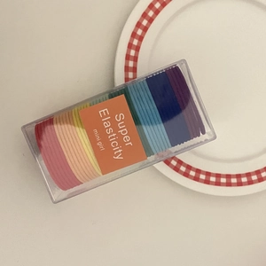 Detailed view of colorful elastic hair ties in a transparent storage box with a mini girl label