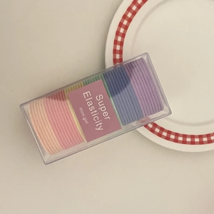 Close-up of candy-colored elastic hair ties in a clear rectangular storage case