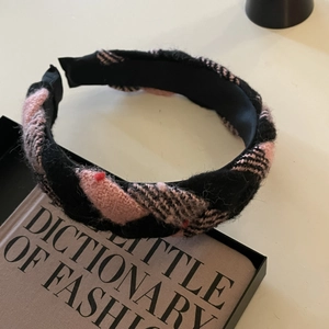 Detailed close-up of pink and black twisted knitted headband with vintage texture on books