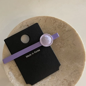 Elegant purple rhinestone hair clip with pearl detailing on a premium marble display tray