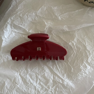 Detailed view of glossy dark red hair claw clip with golden B-shaped metal decoration