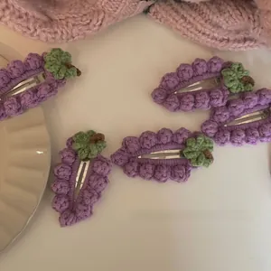 Vue détaillée de cinq barrettes à cheveux en crochet fait main en forme de raisins violets