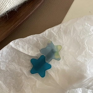 Close-up of star-shaped acetate hair clips in dark green and textured frosted grey