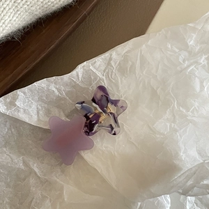Detailed view of two acetate star hair clips in purple and marble texture with gold clips