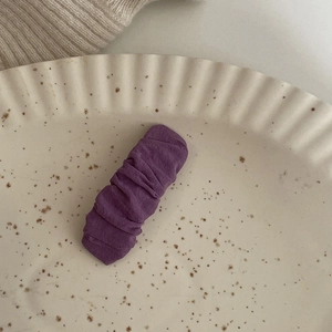 Primo piano di un fermaglio per capelli in tessuto viola con trama increspata stile coreano