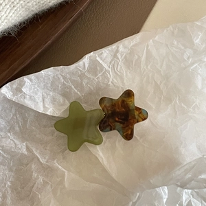 Close-up of star-shaped acetate hair clips in olive green and dark brown tortoise pattern