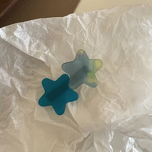 Detail shot of acetate star hair clips in solid teal and marble pattern finish