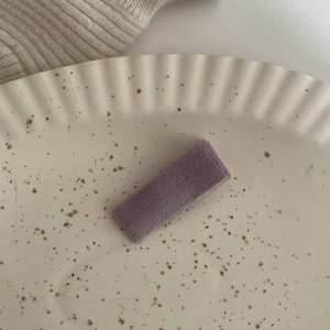 Vista dettagliata di un fermaglio per capelli rettangolare in velluto viola sul vassoio
