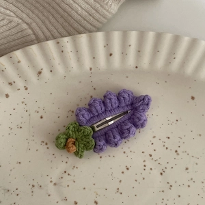 Dettaglio di un fermaglio per capelli viola all'uncinetto con fiore su un piatto