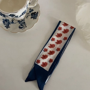 French style silk twilly with blue stripes and red floral patterns on a white table