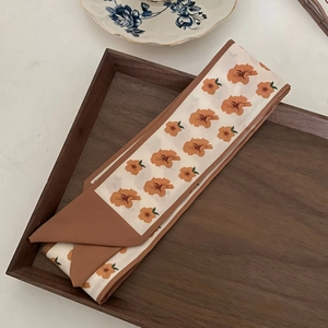 Floral silk twilly scarf in cream and orange, displayed on a wooden tray for hair or bags