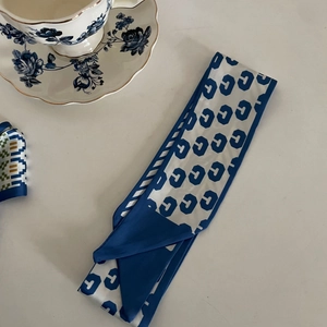 Detail of blue and white geometric pattern narrow silk scarf with diagonal cut ends