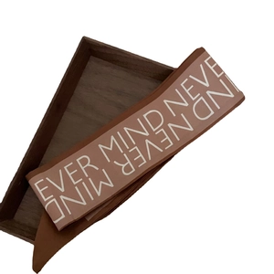 Brown silk scarf with NEVER MIND print on a wooden tray for hair styling or bag accessory