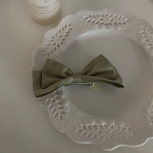 Detailed view of the olive green satin bow hair clip with a metal duckbill clip design