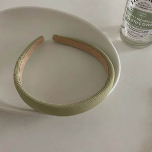Close-up of a thick sage green padded headband with non-slip lining on a white tray