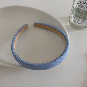 Detail of light blue twill fabric headband with soft texture on a white plate