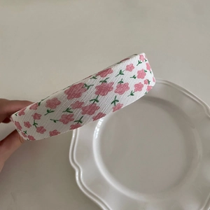 Close-up of floral fabric texture on a wide headband with pink flower patterns