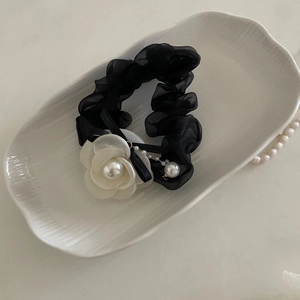 Macro detail of French black organza scrunchie with white camellia flower and pearls