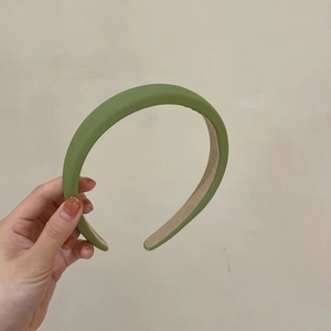 Detail showing the matte avocado green faux leather texture and beige lining of the headband