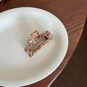 Detail of square acetate hair claw with brown tortoiseshell pattern on white ceramic plate