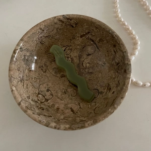 French vintage green wave hair clip with gold lettering on elegant marble bowl