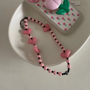 Détail des perles en cœur rose et perles rayées sur une dragonne de téléphone faite à la main
