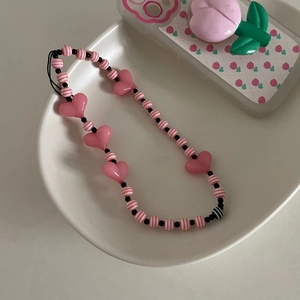 Détail de perles rayées roses et blanches avec cœurs sur un plateau crème