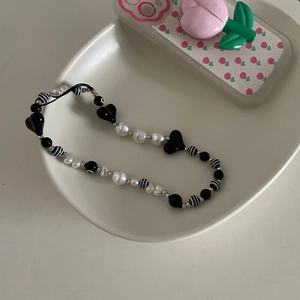 Dragonne de téléphone minimaliste avec perles noires et blanches en forme de cœur