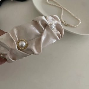 Vue détaillée du serre-tête en satin champagne avec motif cœurs et perles encadrées
