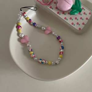 Gros plan sur une dragonne de téléphone en perles colorées avec cœurs roses et perles