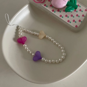 Détail d'une dragonne de téléphone en perles blanches et cœurs en résine colorée