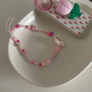 Gros plan sur la dragonne rose avec perles en forme de fraise, fleur et lettres Nana