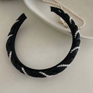 Détail d'un élégant serre-tête tressé en satin noir orné de petites perles blanches