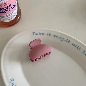 Detailed view of matte pink macaron hair claw clip on a white decorative ceramic plate