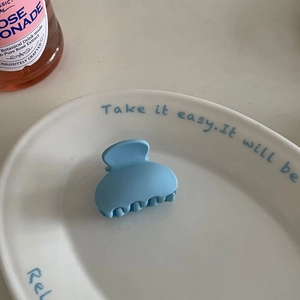 Close-up of light blue matte hair claw clip on a ceramic tray with wave-tooth design
