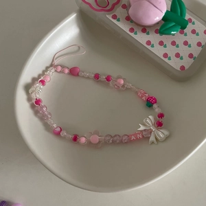 Vue détaillée de la dragonne de téléphone en perles avec fleurs roses et nœud blanc