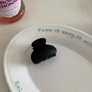 Close-up of matte black hair claw clip with a serrated grip design on a ceramic plate