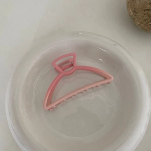 Pince à cheveux mate rose dégradée dans un plat en céramique minimaliste pour coiffure
