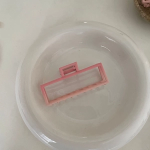 Pince à cheveux rectangulaire rose avec design géométrique sur assiette en céramique