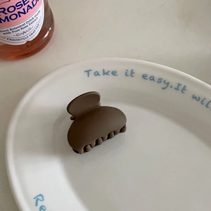 Detail view of a matte brown claw clip on a decorative plate for high ponytail styling