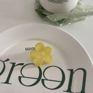 Gros plan d'une pince à cheveux fleur jaune translucide sur un plateau décoratif