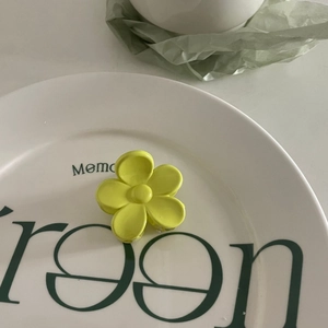 Gros plan d'une pince à cheveux fleur jaune brillante posée sur une assiette en céramique