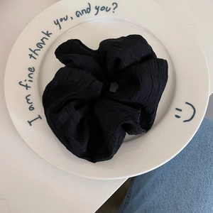 Detail shot of black pleated fabric scrunchie with French INS style texture on a plate