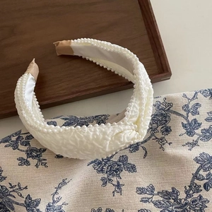 Detail view of French pleated headband with white pearl trim and quilted fabric texture